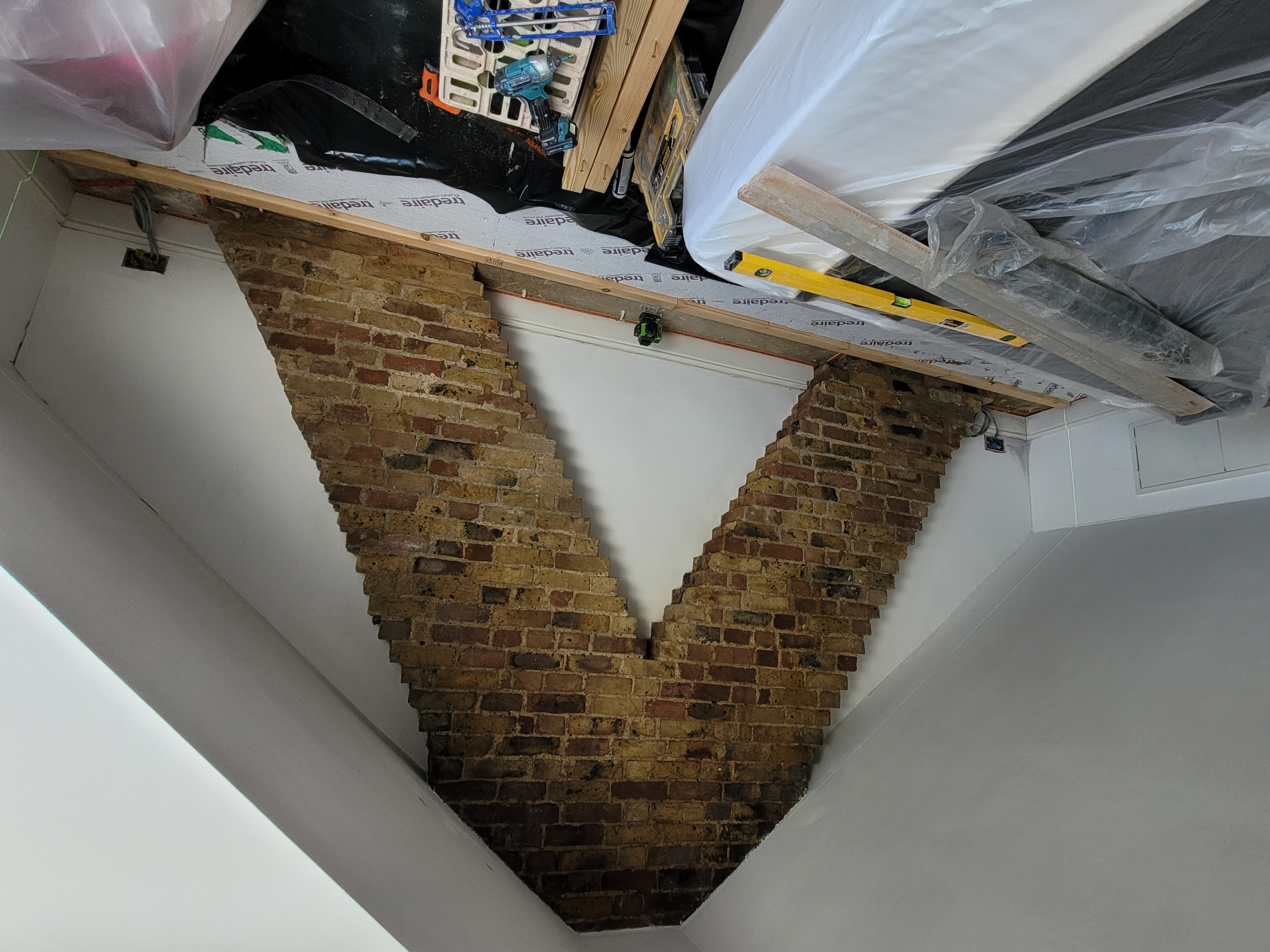 An attic space with bricks shaped like the top of an arrow on a wall for aesthetics